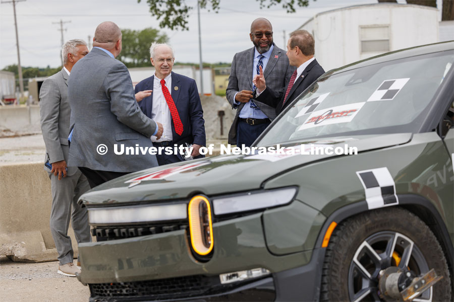 NU President Jeffrey Gold (left wearing red tie), and UNL Chancellor Rodney Bennett (right wearing sunglasses), discuss the results of the EV crash with officials from the University of Nebraska-Lincoln’s Midwest Roadside Safety Facility. In research sponsored by the U.S. Army Engineer Research and Development Center, the University of Nebraska-Lincoln’s Midwest Roadside Safety Facility is investigating the safety questions raised by the burgeoning number of electric vehicles on the nation’s roadways by performing crash test performed on a guardrail at 62 mph, the 7,000-plus-pound, Rivian R1T truck crashed into a temporary barrier. The barrier deflected several feet but the truck did not go through the barrier. July 1, 2024. Photo by Craig Chandler / University Communication and Marketing.