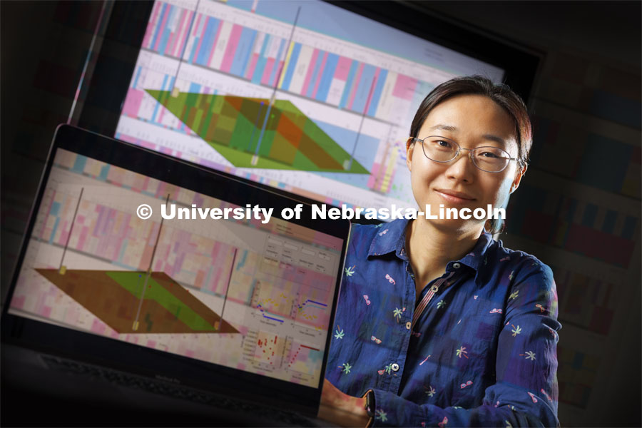 Shuai Nie is a CAREER award winner, Nie is an Assistant Professor in the School of Computing. Her research focuses on reliable wideband connectivity (especially in rural areas). On the screens is a graphic detailing the connectivity of the phenotyping spider cam at ENREEC. A color chart of US frequency allocations overlays the image. July 11, 2024. Photo by Craig Chandler / University Communication and Marketing.