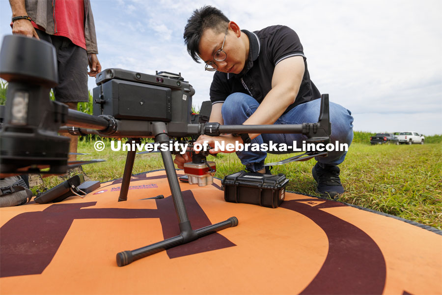 Biquan Zhao, Post-Doc Research Associate in Animal Science, attaches a multispectral camera to a drone to fly over the corn fields northeast of 84th and Havelock to record the growth of the fields. July 16, 2024.  Photo by Craig Chandler / University Communication and Marketing