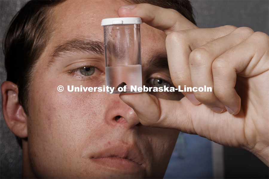 Joe Stalder, a senior in geology and UCARE student, looks at a seed from a soil sample. Jim Benes, a geography Ph.D. student in the School of Global Integrative Studies, said the seed hasn’t been carbon dated yet, but he estimated it is between 125-500 years old. Benes works with UCARE students Jasmine Pham and Joe Stalder in the same Bessey Hall lab Benes worked in as an undergrad. July 18, 2024. Photo by Craig Chandler / University Communication and Marketing.