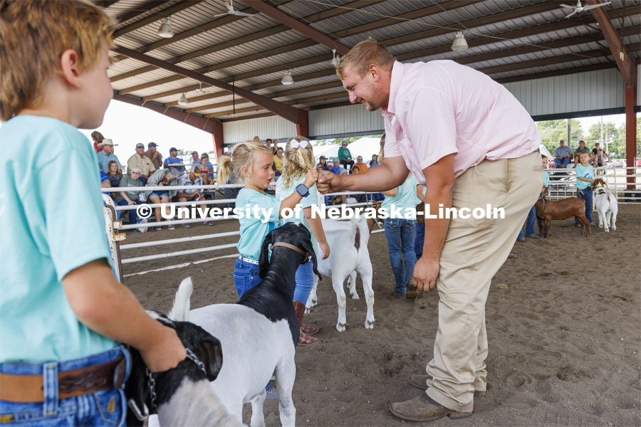 Goat judge John Alfs fist bumps with Ivy Mentink, 5, during Clover Kid competition. 4-H Polk County Fair in Osceola, Nebraska. July 19, 2024. Photo by Craig Chandler / University Communication and Marketing.