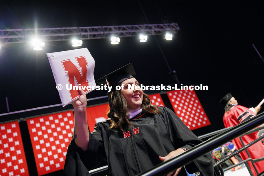 Melissa Villarreal shows off her masters diploma to family and friends. Summer Commencement ceremony in Pinnacle Bank Arena. August 17, 2024. Photo by Craig Chandler / University Communication and Marketing.