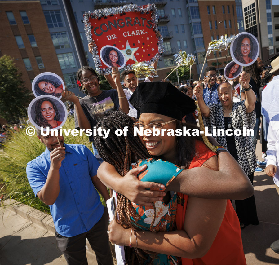 Genese Clark is hugged by family and friends as her cheering section celebrates her doctoral degree outside PBA. Summer Commencement ceremony in Pinnacle Bank Arena. August 17, 2024. Photo by Craig Chandler / University Communication and Marketing.