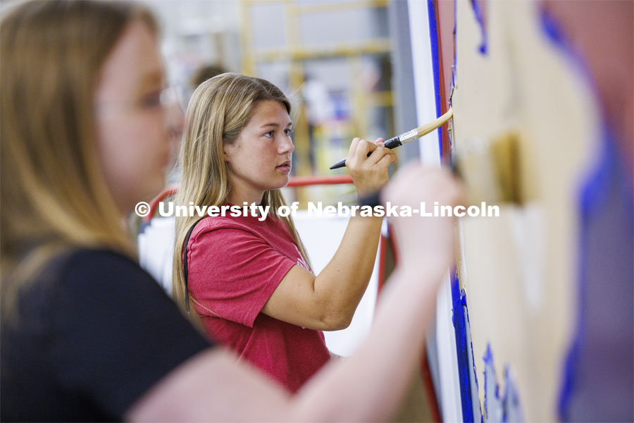 Taylor Clark paints on a multi-colored wall along with her fellow 1L students. The first-year College of Law students spent half of their Thursday painting interior walls at the Habitat for Humanity of Lincoln ReStore. August 22, 2024. Photo by Craig Chandler / University Communication and Marketing.