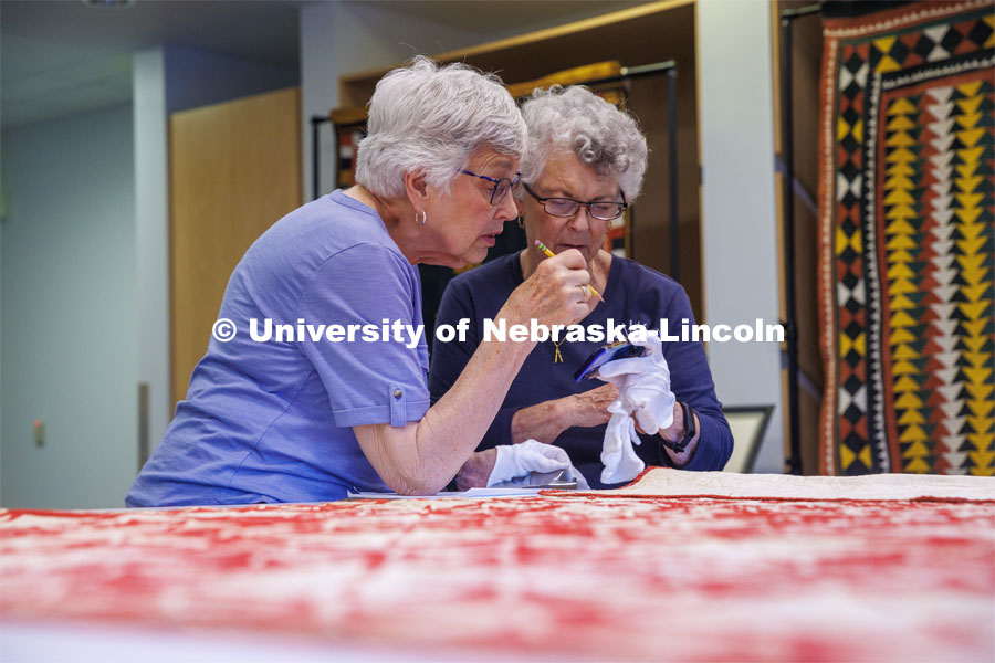 Volunteers Susan Macy (left) and Carolyn Kitterer look at a photo of the quilt on Carolyn’s phone to read the name easier. International Quilt Study Center and Museum Genealogical Task Force. August 29, 2024. Photo by Kristen Labadie / University Communication.