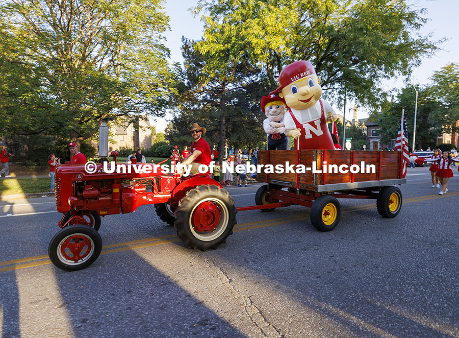 Husker cheer coach Jake Jundt pulls Herbie Husker and Lil’ Red using his family’s tractor and wagon. Cornchella Homecoming Parade and Cornstock. October 4, 2024. Photo by Craig Chandler / University Communication and Marketing.