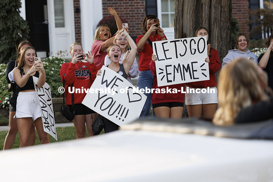 Grace Roberts, Kelli Kaufman and Madeline Petton hold signs to celebrate Homecoming Royalty Emmerson Putnam as she is driven past their Gamma Phi Beta sorority. Cornchella Homecoming Parade and Cornstock. October 4, 2024. Photo by Craig Chandler / University Communication and Marketing.