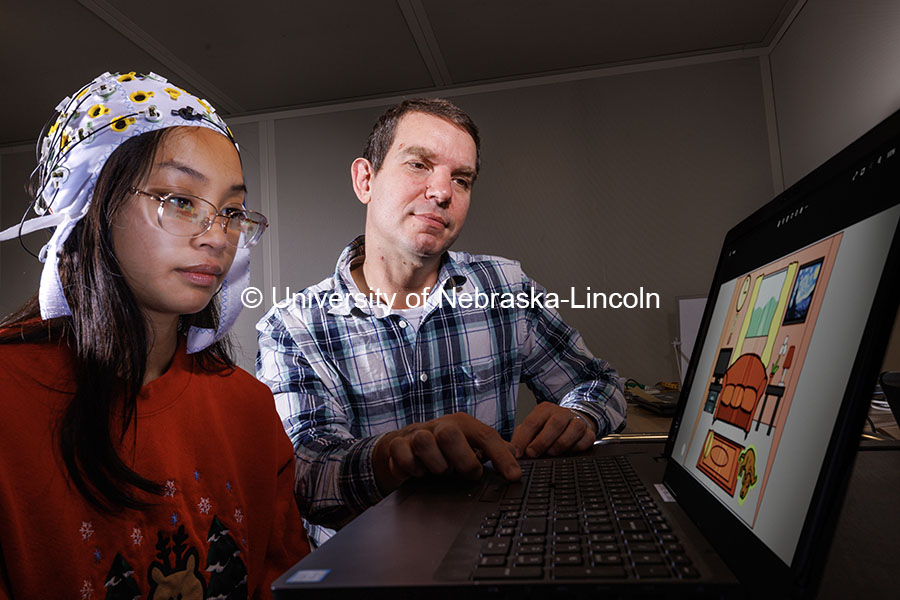 Kevin Pitt, Assistant Professor Special Education and Communication Disorders, demonstrates an electrode cap in the AAC Translation Lab with Aliyah Muniz, senior in communication science disorders. The subject views an image to see how the brain reacts when one object is highlighted. November 1, 2024. Photo by Craig Chandler / University Communication.