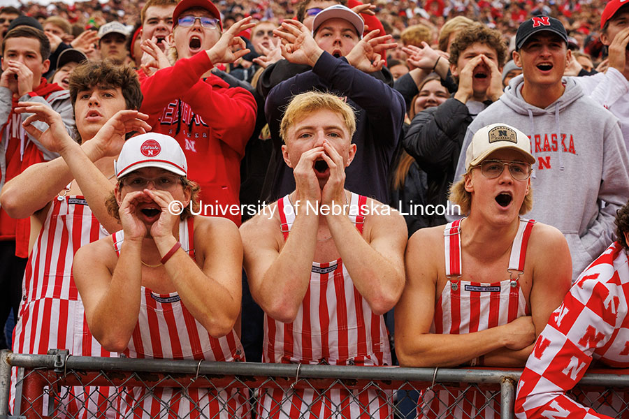 Fans in red and white striped overalls cheer in the student section at the Nebraska vs UCLA football game. November 2, 2024. Photo by Kristen Labadie / University Communication.