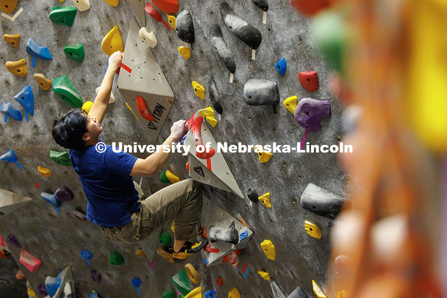 Andy Tran, freshman, climbs up the wall in the Campus Recreation facility on City Campus. The League of Extraordinary Boulderers program is designed to teach participants climbing techniques and build friendships with others interested in bouldering. November 20, 2024. Photo by Jordan Opp / University Communication and Marketing.