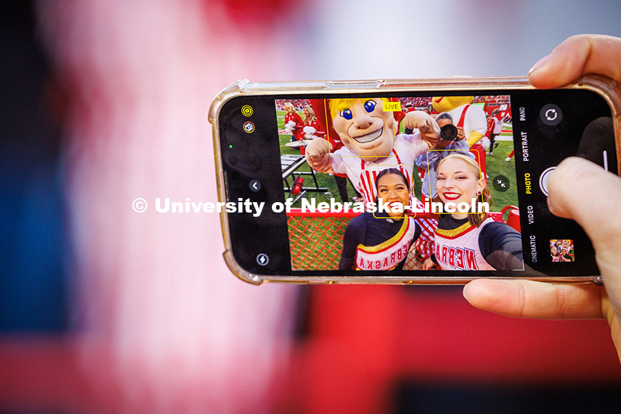 Nikki Duero (left) and Megan Timm, seniors on the UNL Color Guard, snap a selfie with Herbie Husker at the Huskers vs. Wisconsin football game. November 23, 2024. Photo by Kristen Labadie / University Communication.