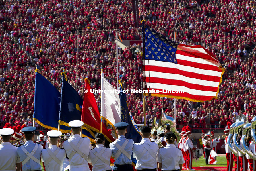 Sunlight glows thorugh the flag during the National Anthem. Nebraska vs. Wyoming football. September