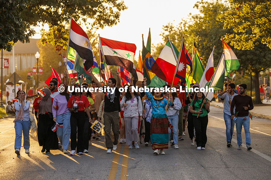 International Students and their flags are lighted by the setting sun as they march in the homecomin