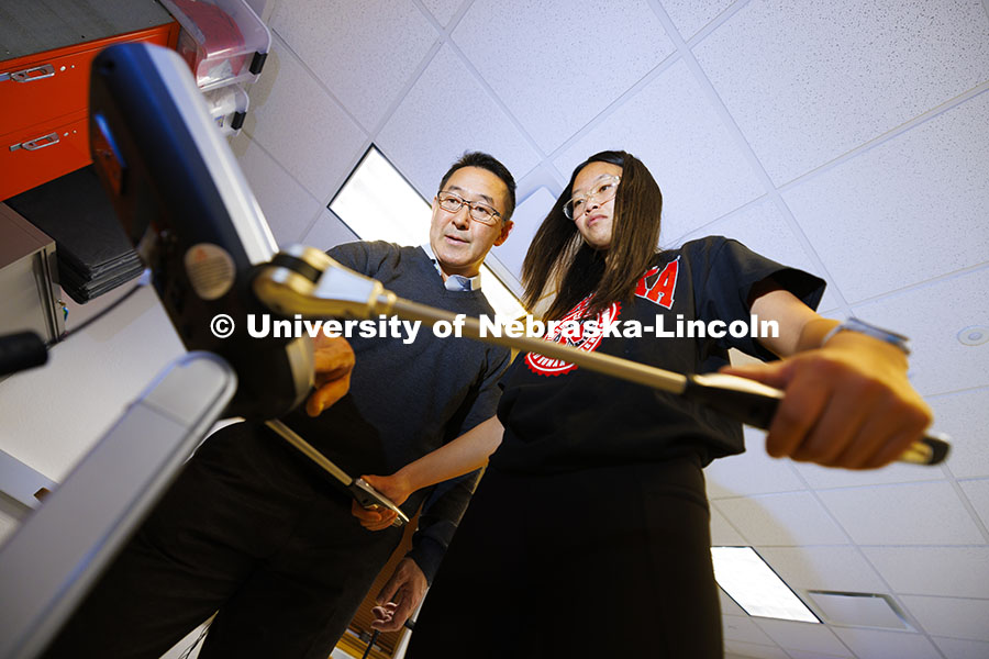 Lauren Marshall grips a device that uses a small electric current to measure body fat as Shinya Taka