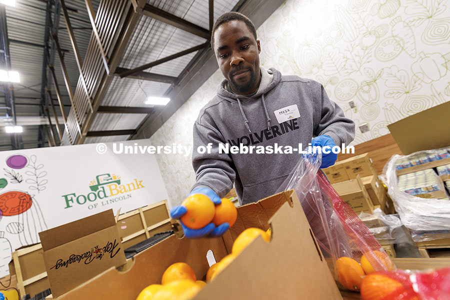 Nosakhare Idiaghe, graduate student in Engineering, places oranges into a bag during SLICE’s Engag