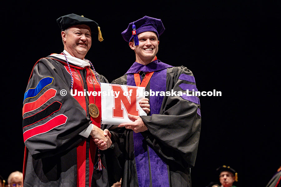 250503_Law_Commencement_0837.jpg (Left) Robert Schafer, a chairman on UNL’s Board of Regents, hands his son, Nolan Schafer his law