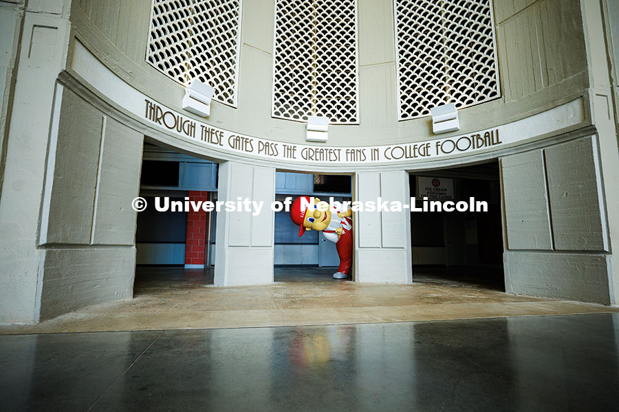250506_Mascot_Reveal_332.jpg Ben Hastreiter as ‘Lil Red peaks out from behind a column in Memorial Stadium. Hastreiter has been
