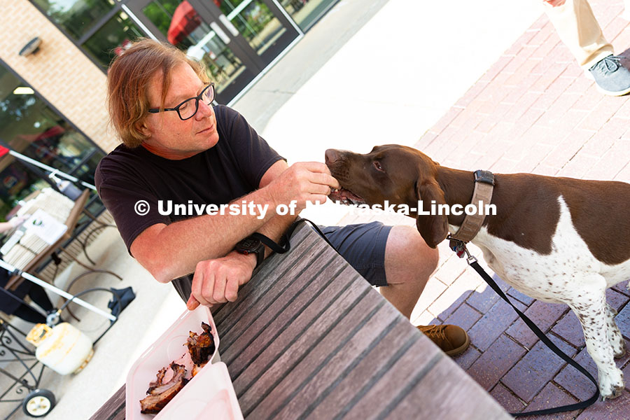 250529_Grill_Out_9327.jpg Andy Agena gives Gaspard, a French pointer, a taste of his smoked ribs at the first of East Campus D