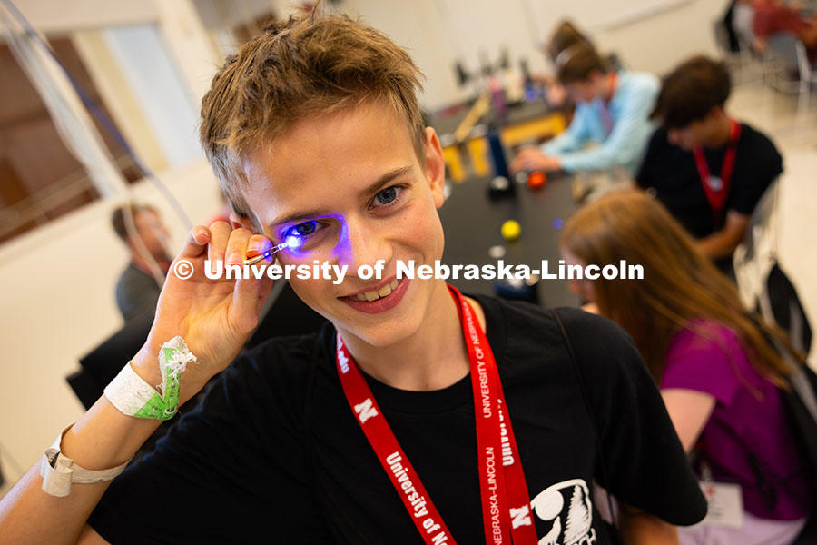 250610_Big_Red_Camps_9998.jpg Austin Vaughan holds a blue LED light connected to a small battery up to his eye during an engineeri