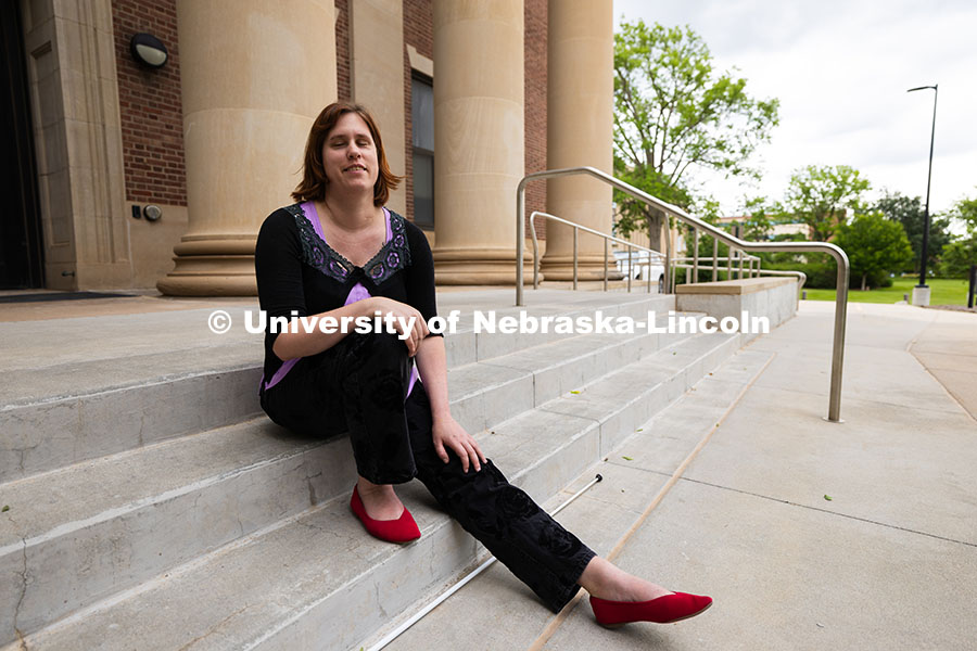250617_Kelly_Coleman_0621.jpg Kelly Coleman is seated on the steps outside of Louise Pound Hall, where she works in Services for S