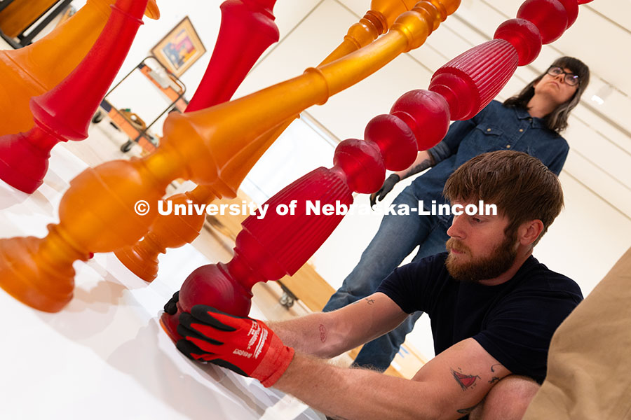 Quentin Fortney, an on-call exhibition technician for the Sheldon Museum of Art, fits part of Niho K
