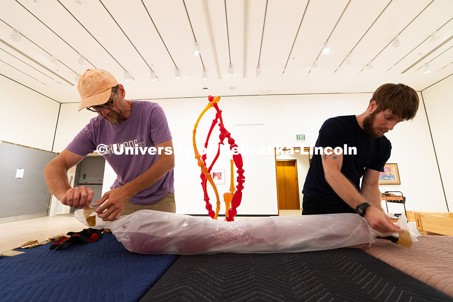 Delan Lonowski (left) and Quentin Fortney (right), on-call exhibition technicians, unwrap part of Ni