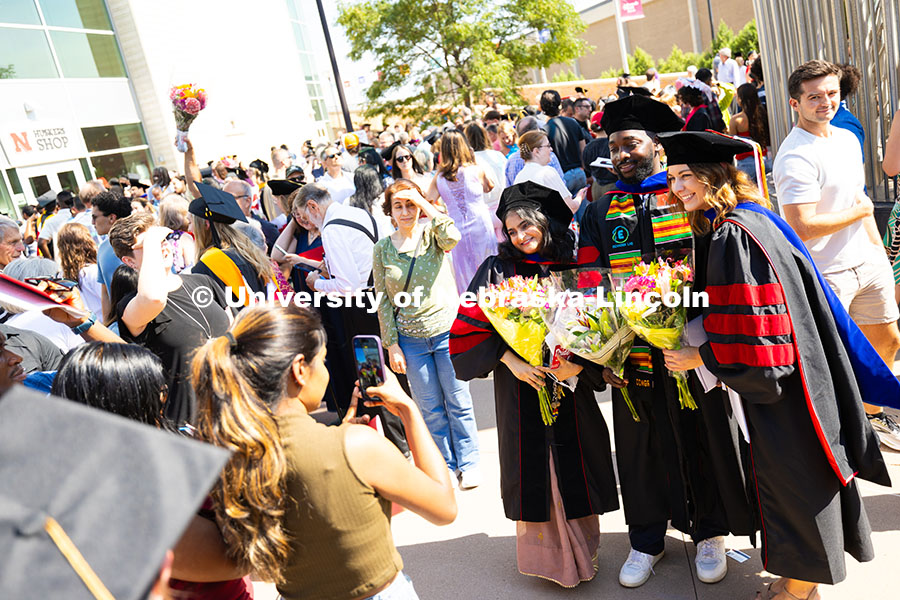 250816_Commencement_3760.jpg Graduates pose together outside of Pinnacle Bank Arena as other families look for loved ones in the