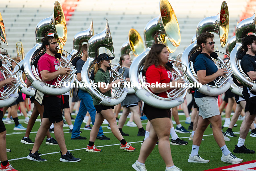 Tuba players march during a balance-building exercise during rehearsal on the field in Memorial Stad