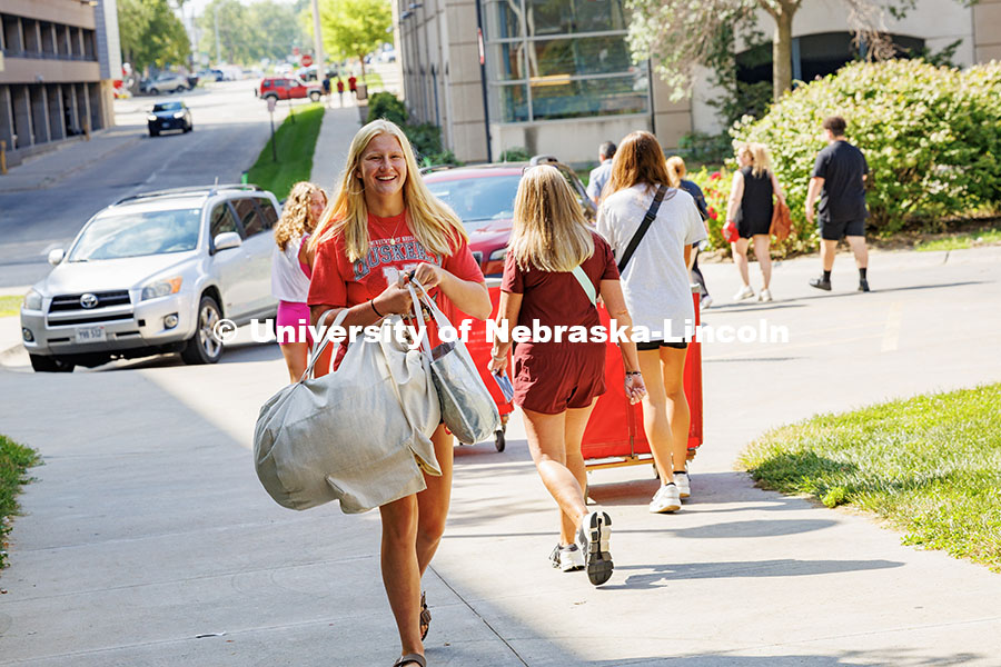 250820_Move_In_507.jpg Alaina Hadford smiles as she carries her items into University Suites during move-in day. Residence