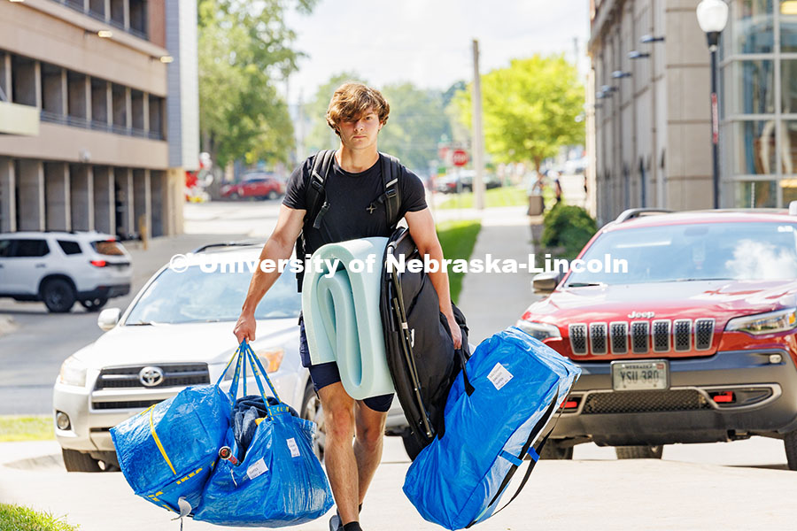 250820_Move_In_588.jpg Carsen Davis carries several blue bags into University Suites on move-in day. Residence hall move-in