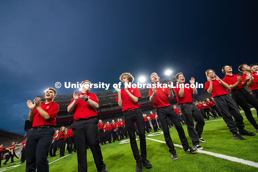 Members of the pit clap their hands as the marching band comes together for "Hey Baby" toward the en