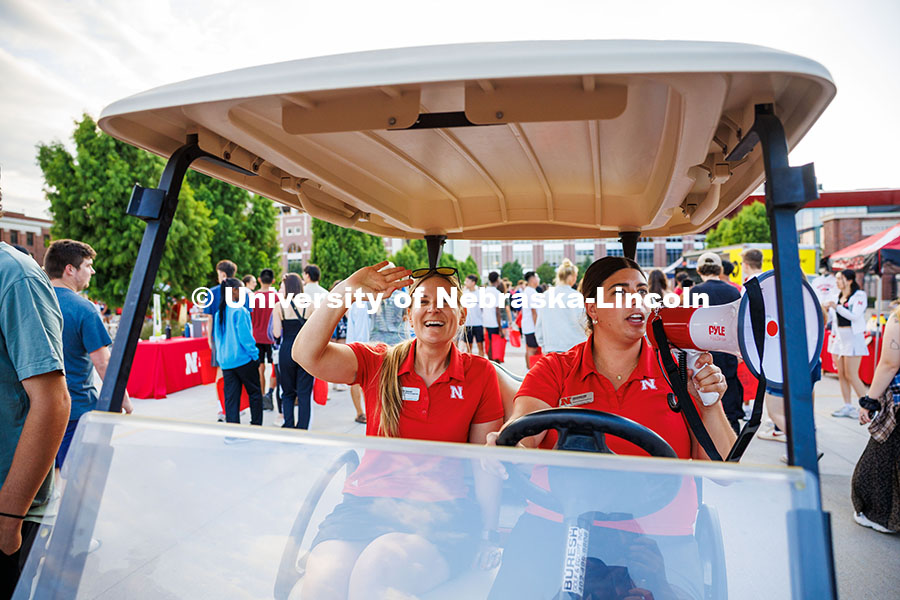 Staff members Hollie Swanson (left) and Kalan Walters drive a golf cart through the Big Red Welcome 