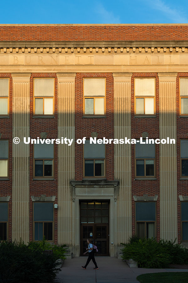 A student walks to class in front of Burnett Hall as the sun rises on city campus. September 11, 202