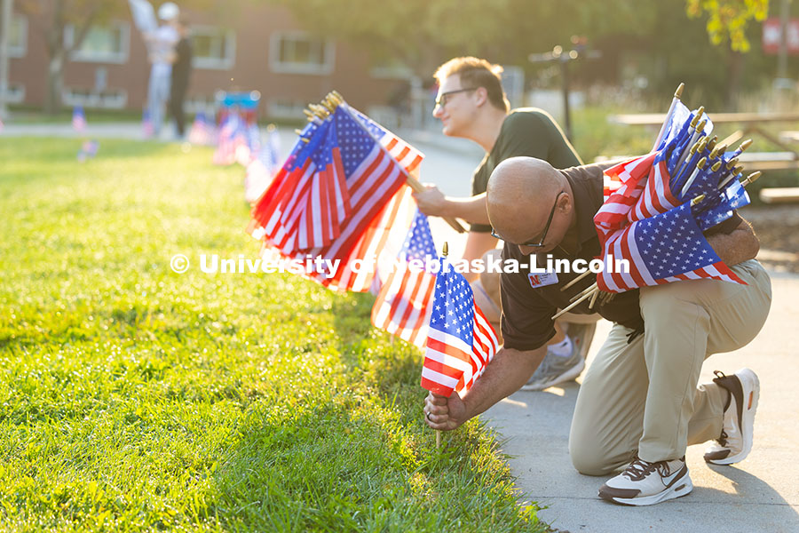 TJ McDowell, Assistant Vice Chancellor/Dean of Students, places flags in the ground alongside Ethan 