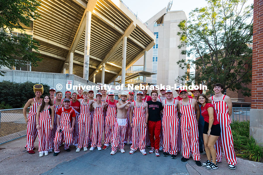 Husker students wear bibs and pose for a group photo outside of Memorial Stadium before the football