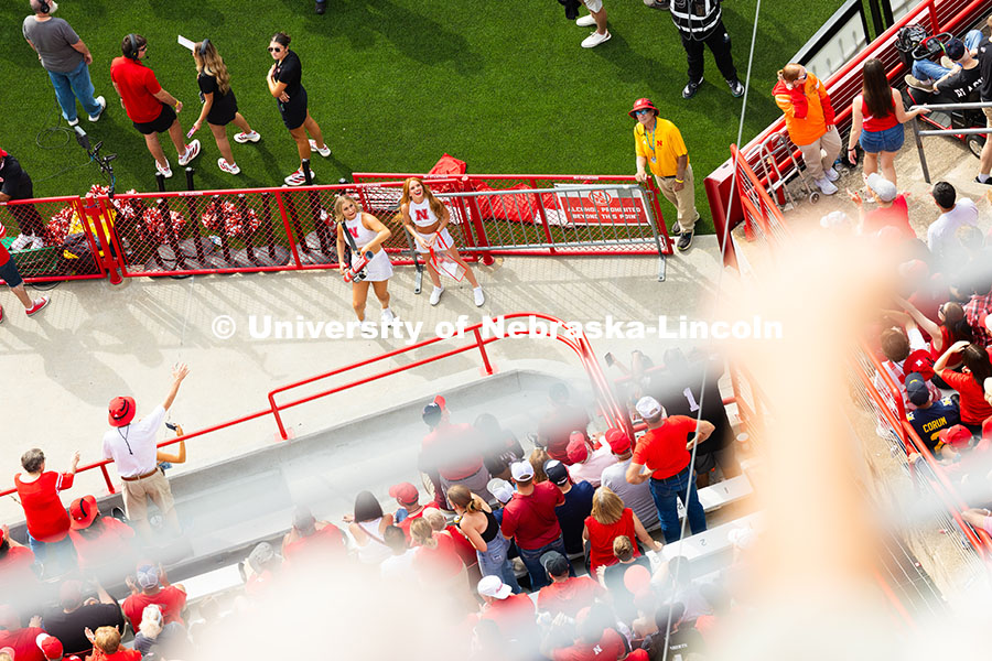 Husker fans hold out their hands as two members of the spirit squad launch t-shirts into the crowd. 