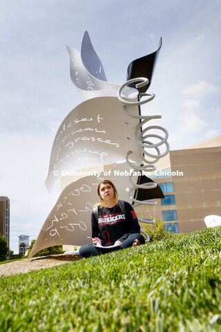 Kayla Schreck, a sophomore in Interior Design, sits in the shade of the Torn Notebook while sketchin