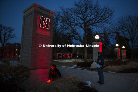 Workers installing lights on the East Campus gateway / entrance columns for Glow Big Red. Glow Big R