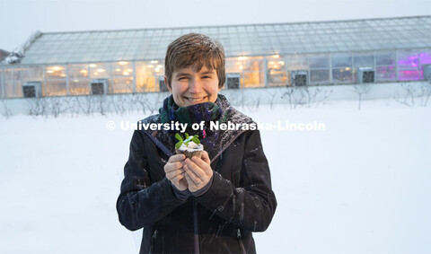 Rebecca Roston, assistant professor of biochemistry, holds a pea plant outside the Beadle Hall green