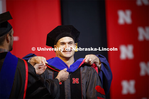 Mateusz Mittek receives his hood at the Graduate Commencement and Hooding at the Pinnacle Bank Arena