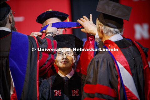 Dian Peng watches as her hood is lowered over her head at the Graduate Commencement and Hooding at t