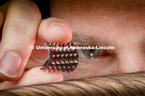 Graduate student Jordan Rosenbohm holds a flexible prototype for a smart bandage with tiny 3-D print