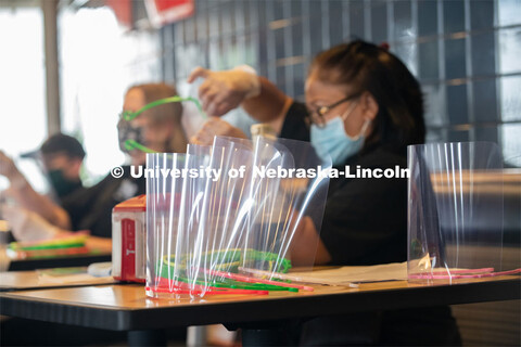 Dinning Services employees, Rochan Pinho, Janet Nichols and Dami Olsen, assemble face shields at Har