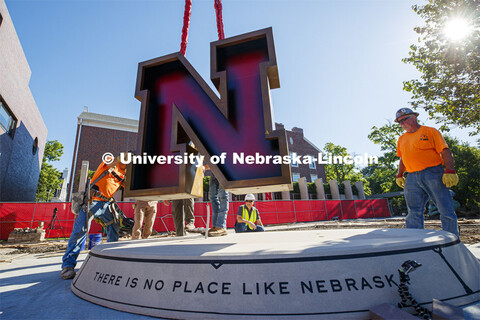 Artist, Matthew Placzek (in white hard hat) watches as the new stainless-steel N for the centerpiece