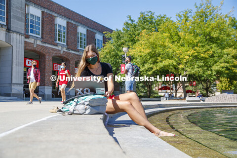 A young woman soaks her feet in the Broyhill fountain while working on her laptop computer. Photo sh