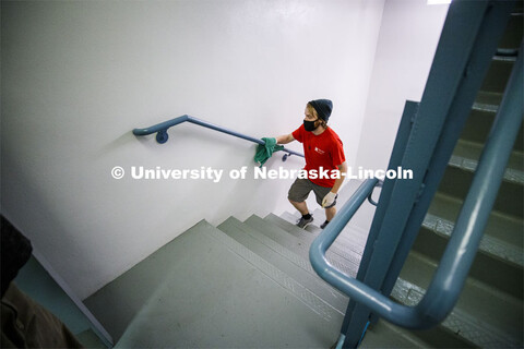 Kenny Shuman, a housing student worker, wipes down the stairway railings to keep move in clean. Firs