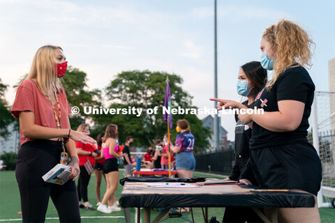 Members of the Nebraska Barbell Club (right) speak to a student during the HuskerMania Masker Singer