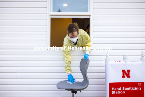 Stephanie Padilla, R.N.. leans out of the testing pod to sanitize the seat walk-up participants sit 
