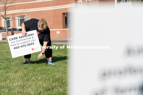 CARE Advocate Melissa Wilkerson places a sign at the Nebraska Union Greenspace. Flags and signs are 