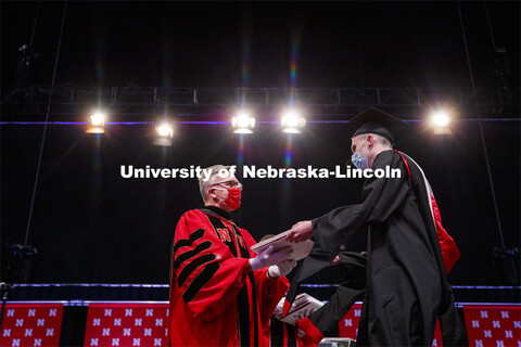 Chancellor Ronnie Green wears gloves to hand each graduate including Misty Sue Pocwierz-Gaines their